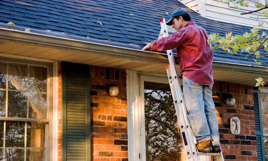 Worker cleaning roof gutters