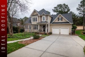 Two-story suburban home with stone and siding exterior, attached two-car garage, concrete driveway, and landscaped front yard on an overcast day.