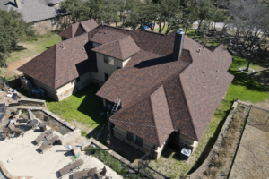 Aerial view of a large house with a brown shingled roof