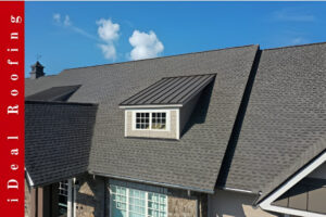 A textured gray roof with a dormer window under a clear blue sky, illustrating a roof repair vs roof replacement scenario, with a red vertical banner reading "iDeal Roofing."