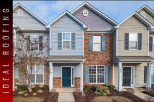 Two-story townhouse with varied facade textures; gray siding, red brick, and a dark blue door. Flanked by similar homes under a clear sky. Text reads "Ideal Roofing."