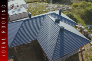Aerial view of newly installed metal roof with modern hip design and chimney vents on a residential home, showcasing professional roof installation and repair work.