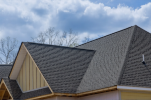 A newly completed asphalt shingle roof under a blue sky, highlighting roofing warranties explained.