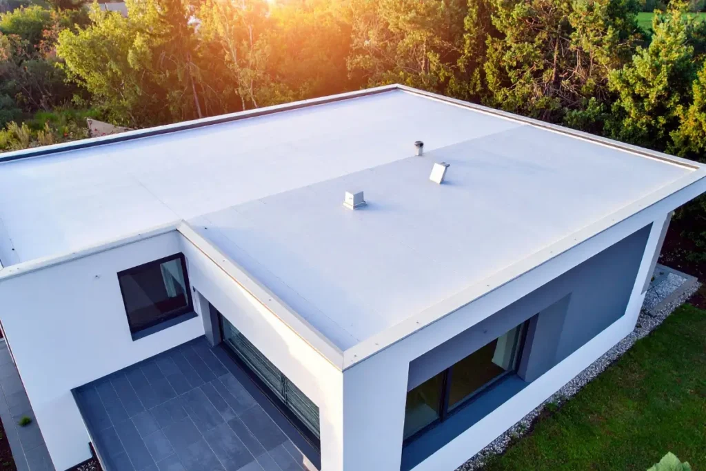 Aerial view of a modern white building with a flat roof surrounded by trees