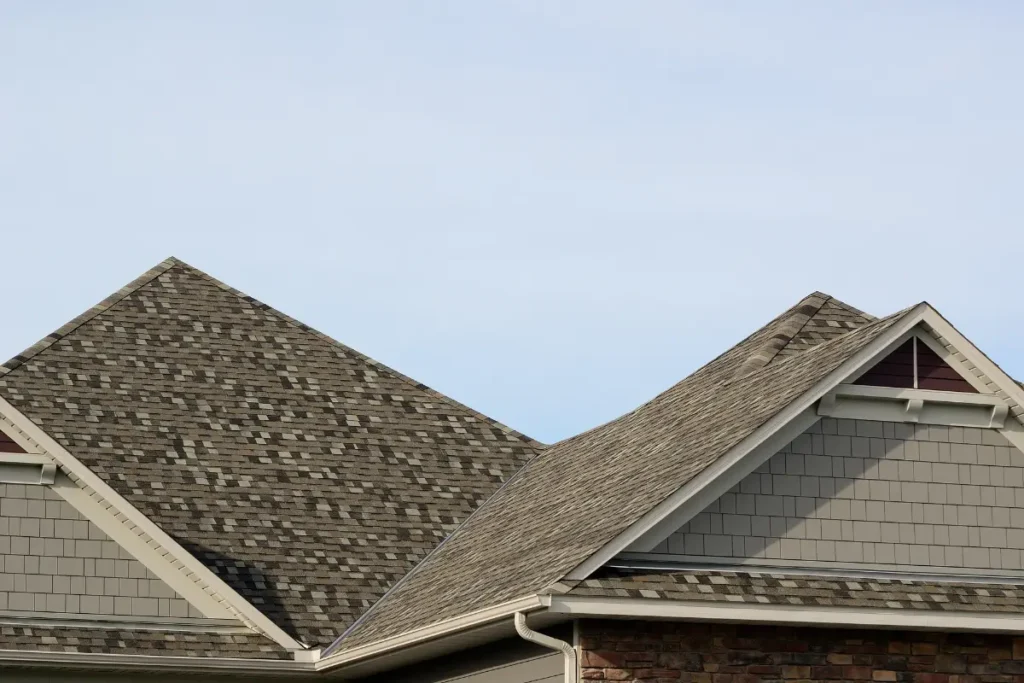 Newly installed brown multi-tone asphalt shingle roof on a residential home with gables and white gutters.
