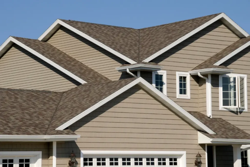 Close-up view of multiple roof gables with brown architectural shingles and white gutters on a modern suburban house.